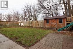 Fenced backyard with a storage unit, a patio area, and a playground - 