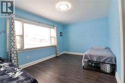 Unfurnished bedroom with dark wood-style floors and baseboards - 