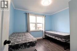 Bedroom with dark wood finished floors and ornamental molding - 