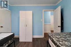 Bedroom featuring dark wood-type flooring, ornamental molding, and a closet - 