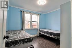 Bedroom featuring dark wood-style floors and crown molding - 