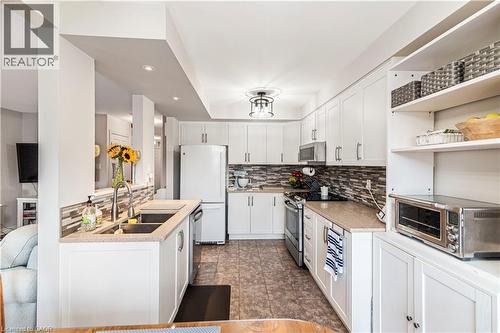 Kitchen with stainless steel appliances, white cabinets, recessed lighting, tasteful backsplash, and open shelves - 311 Highway 8 Unit# 12, Stoney Creek, ON - Indoor Photo Showing Kitchen With Double Sink