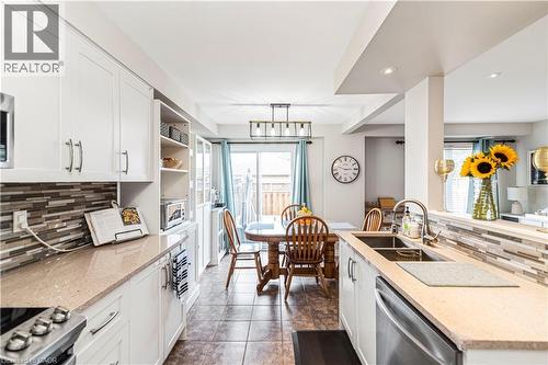Kitchen featuring backsplash, light stone counters, and white cabinetry - 311 Highway 8 Unit# 12, Stoney Creek, ON - Indoor Photo Showing Kitchen With Double Sink