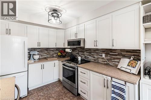 Kitchen featuring stainless steel appliances, white cabinets, and light stone countertops - 311 Highway 8 Unit# 12, Stoney Creek, ON - Indoor Photo Showing Kitchen