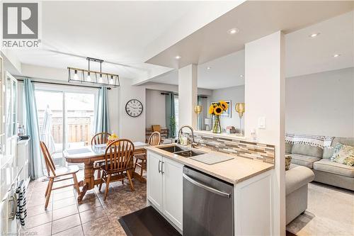 Kitchen featuring open floor plan, stainless steel dishwasher, white cabinetry, light stone countertops, and pendant lighting - 311 Highway 8 Unit# 12, Stoney Creek, ON - Indoor