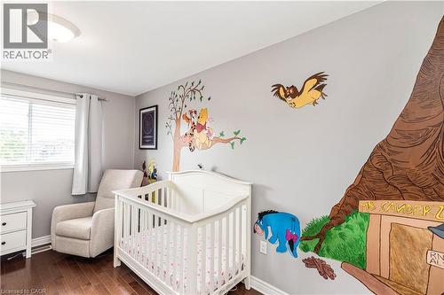 Bedroom featuring dark wood finished floors and a crib - 311 Highway 8 Unit# 12, Stoney Creek, ON - Indoor Photo Showing Bedroom