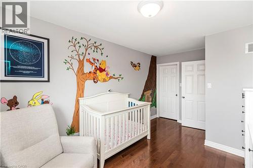 Bedroom with dark wood-style flooring and a crib - 311 Highway 8 Unit# 12, Stoney Creek, ON - Indoor Photo Showing Bedroom