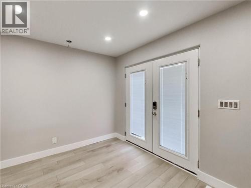 This bright room features light-colored flooring, recessed lighting, and a set of white double doors with integrated blinds - 229 Parkdale Avenue N, Hamilton, ON 