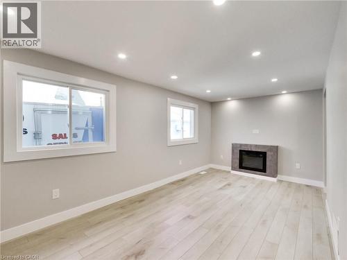 Living area featuring light-colored flooring, recessed lighting, and a modern fireplace with a tiled surround - 229 Parkdale Avenue N, Hamilton, ON 