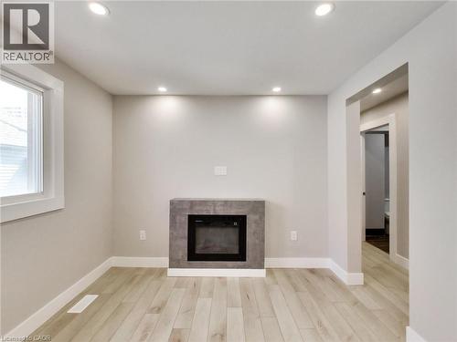 The room features light-colored flooring, recessed lighting, and a modern fireplace with a grey surround - 229 Parkdale Avenue N, Hamilton, ON 