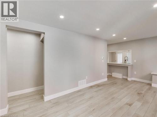 Living area featuring light-toned flooring, recessed lighting, and a pass-through window to the kitchen area - 229 Parkdale Avenue N, Hamilton, ON 