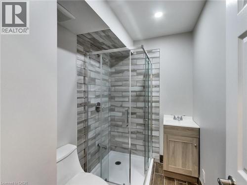 Bathroom with a glass-enclosed shower featuring tiled walls, a vanity with a white countertop, and tiled flooring - 229 Parkdale Avenue N, Hamilton, ON 