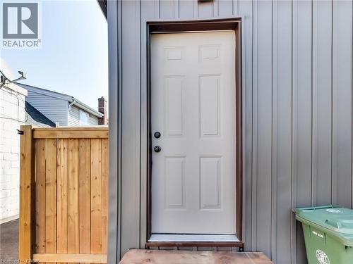 The property features an exterior door with a paneled design, set within a grey vertical siding - 229 Parkdale Avenue N, Hamilton, ON 
