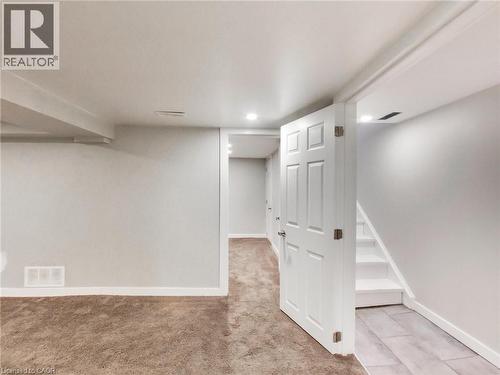 This finished space features plush carpeting, recessed lighting, and a white paneled door - 229 Parkdale Avenue N, Hamilton, ON 