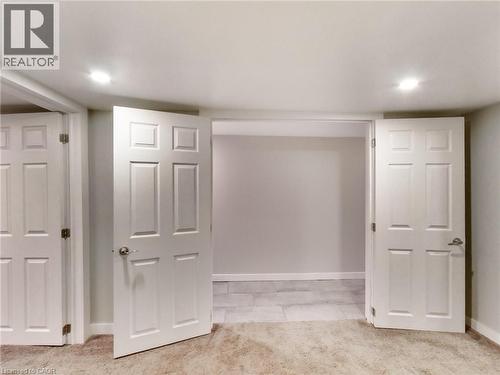 This interior space features recessed lighting and white panel doors, with a carpeted area leading into a section with tiled flooring - 229 Parkdale Avenue N, Hamilton, ON 