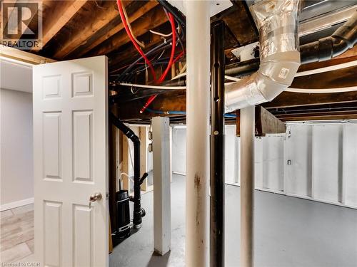 The unfinished basement offers visible ceiling joists, exposed ductwork, and painted concrete floors - 229 Parkdale Avenue N, Hamilton, ON 