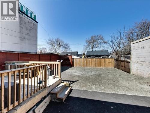 The property features a wooden deck with railing and stairs, leading to an open outdoor area - 229 Parkdale Avenue N, Hamilton, ON 