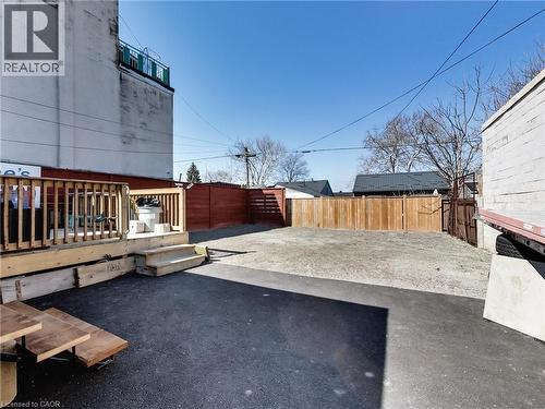 The property features an outdoor wooden deck with railings, concrete steps, and a paved area - 229 Parkdale Avenue N, Hamilton, ON 