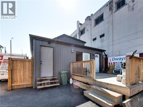 The property features an exterior with gray siding, a wooden fence, and a wooden deck - 229 Parkdale Avenue N, Hamilton, ON 