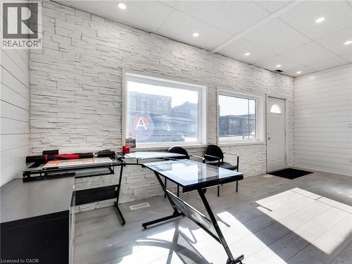 This interior space features textured white brick walls, light-colored flooring, and large windows that provide ample natural light - 229 Parkdale Avenue N, Hamilton, ON 