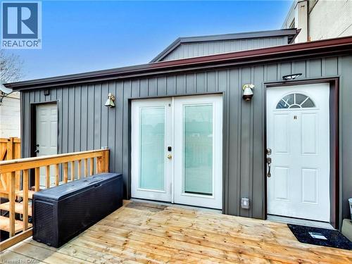 The property features a wooden deck with a wooden railing, a dark grey facade, and multiple white exterior doors - 229 Parkdale Avenue N, Hamilton, ON 