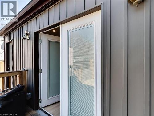 The property features a private exterior entrance with a wood deck and an overhead exterior light fixture - 229 Parkdale Avenue N, Hamilton, ON 