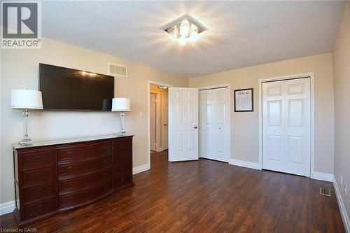 Unfurnished bedroom with a textured ceiling, two closets, and dark wood finished floors - 2206 Donald Road, Burlington, ON - Indoor