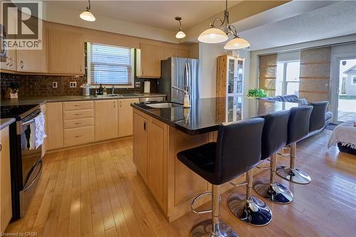 Kitchen featuring stainless steel appliances, light wood finish cabinetry, open floor plan, dark stone countertops, and a breakfast bar - 126 Snowdrop Crescent, Kitchener, ON - Indoor Photo Showing Kitchen With Stainless Steel Kitchen