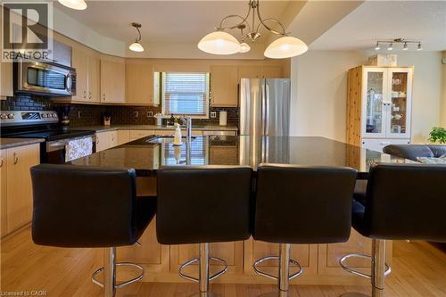 Kitchen featuring stainless steel appliances, light wood finished floors, pendant lighting, dark stone countertops, and backsplash - 126 Snowdrop Crescent, Kitchener, ON - Indoor Photo Showing Kitchen With Stainless Steel Kitchen