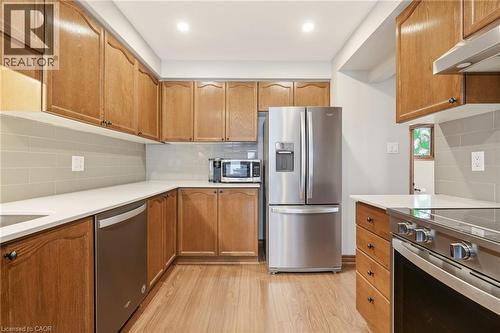 The kitchen features hardwood flooring, wooden cabinetry, and stainless steel appliances, including a refrigerator, dishwasher, and stove - 1 Tomahawk Drive, Grimsby, ON - Indoor Photo Showing Kitchen With Stainless Steel Kitchen