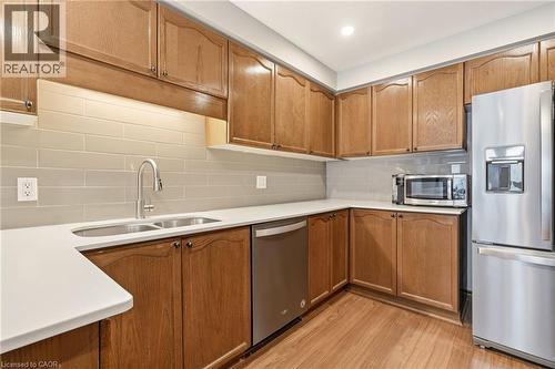 The kitchen features wood cabinetry, light countertops, a stainless steel refrigerator, and a double basin sink - 1 Tomahawk Drive, Grimsby, ON - Indoor Photo Showing Kitchen With Stainless Steel Kitchen With Double Sink