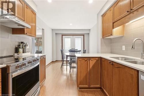 The kitchen features wood cabinetry, light countertops, and a stainless steel oven - 1 Tomahawk Drive, Grimsby, ON - Indoor Photo Showing Kitchen With Double Sink