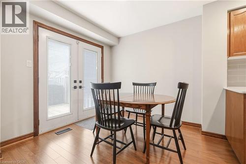 This inviting dining area features hardwood floors, light-colored walls, and a pair of white French doors with integrated blinds that open to an outdoor space - 1 Tomahawk Drive, Grimsby, ON - Indoor Photo Showing Dining Room
