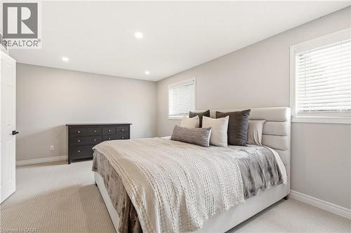 The property features a bedroom with light-colored carpeted flooring, two windows with blinds, and recessed lighting in the ceiling - 1 Tomahawk Drive, Grimsby, ON - Indoor Photo Showing Bedroom