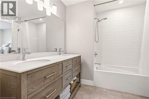 Bathroom featuring a double vanity with a light wood finish, white countertops, two sinks, and a large mirror - 1 Tomahawk Drive, Grimsby, ON - Indoor Photo Showing Bathroom