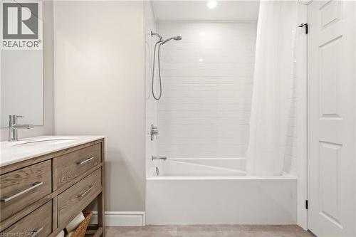 The bathroom features a vanity with a white countertop and a rectangular sink, accompanied by a wall-mounted mirror - 1 Tomahawk Drive, Grimsby, ON - Indoor Photo Showing Bathroom