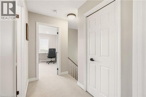 Well-lit hallway featuring light-colored carpet flooring, white trim, and a contemporary ceiling light fixture - 1 Tomahawk Drive, Grimsby, ON - Indoor