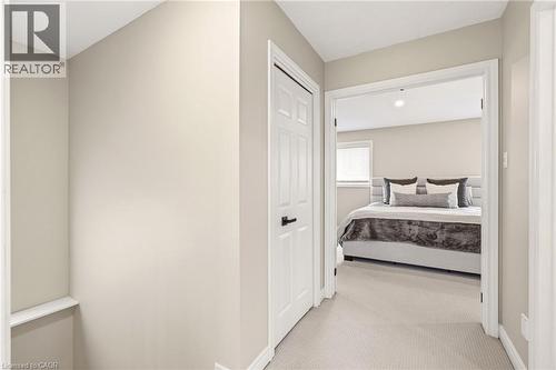 The property features a hallway with light-colored walls and carpeted flooring, leading to a room with a window and a bed - 1 Tomahawk Drive, Grimsby, ON - Indoor Photo Showing Bedroom