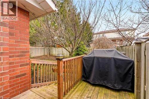 The property features a wood deck with a railing, a red brick exterior, and a fenced yard with mature trees - 1 Tomahawk Drive, Grimsby, ON - Outdoor With Deck Patio Veranda With Exterior