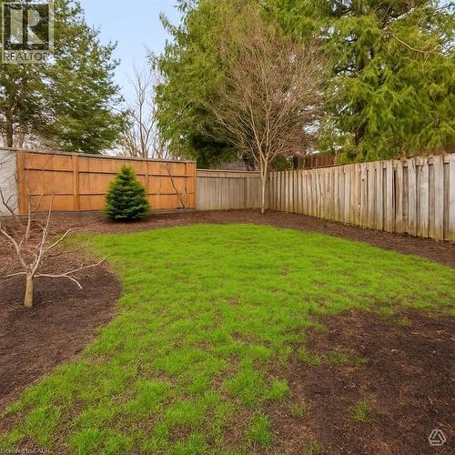 The property includes a fenced yard with a lush green lawn and garden beds - 1 Tomahawk Drive, Grimsby, ON - Outdoor