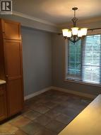 Unfurnished dining area with ornamental molding, suspended lighting, and dark tile patterned floors - 