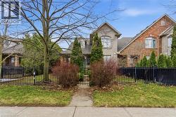 View of front of home with a fenced front yard, brick siding, a shingled roof, and a gate - 