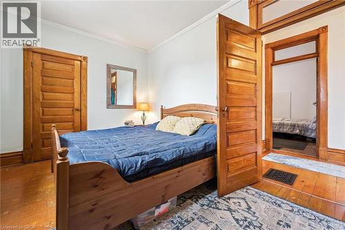 The room features warm hardwood flooring, a bed frame with a natural wood finish, and matching natural wood doors - 155 Lancaster Street E, Kitchener, ON - Indoor Photo Showing Bedroom