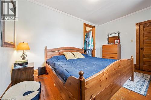 This room features warm-toned wood floors and a matching bed frame, complemented by a solid wood door with intricate detailing - 155 Lancaster Street E, Kitchener, ON - Indoor Photo Showing Bedroom