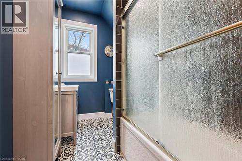 Bathroom featuring patterned floor tiles, a window providing natural light, a vanity with a sink, and a shower with a textured glass enclosure - 155 Lancaster Street E, Kitchener, ON - 