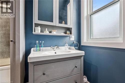 The bathroom features a grey vanity with a white countertop and sink, a mirrored cabinet with an open shelf, and a window with frosted glass - 155 Lancaster Street E, Kitchener, ON - Indoor Photo Showing Bathroom