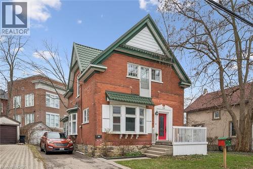 The property features a brick exterior with a distinctive green roof and white trim - 155 Lancaster Street E, Kitchener, ON - Outdoor