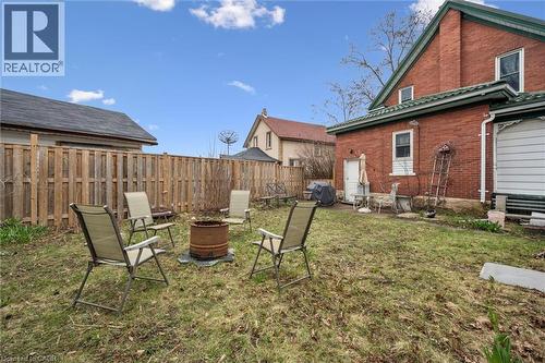 The property features an expansive yard with a lawn, a wooden privacy fence, and a brick exterior with white trim - 155 Lancaster Street E, Kitchener, ON - Outdoor With Exterior