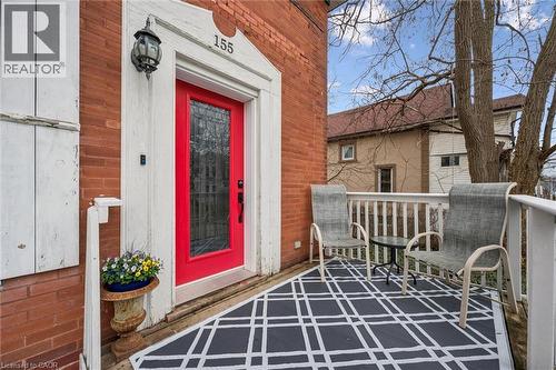 The property features a brick exterior with white trim and a vibrant red front door, complemented by a front porch with a white railing - 155 Lancaster Street E, Kitchener, ON - Outdoor