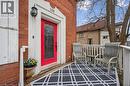 The property features a brick exterior with white trim and a vibrant red front door, complemented by a front porch with a white railing - 155 Lancaster Street E, Kitchener, ON  - Outdoor 